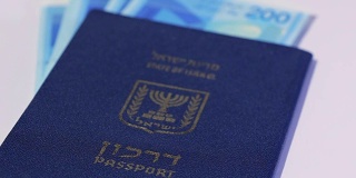 一堆以色列的200谢克尔纸币和以色列护照——潘离开了