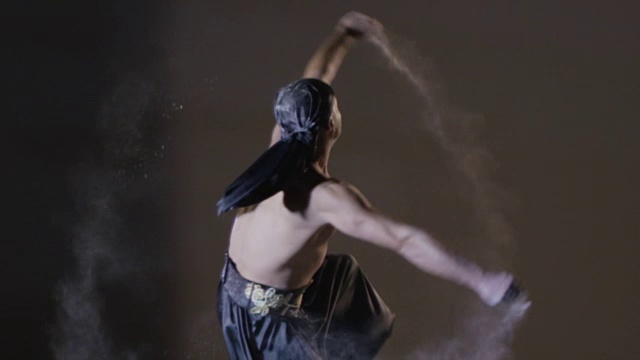 民族舞蹈。在灰色背景上，人与沙共舞。用RED EPIC DRAGON电影摄影机慢动作拍摄。