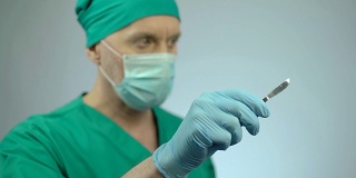 专注的男性外科医生手持锋利的手术刀，点头开始手术
