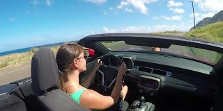 慢镜头:快乐的女人开车在海边的路上，享受着阳光明媚的夏日