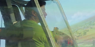 年轻人通过飞行模拟器窗口观看绿色景观，航空