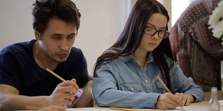 专注的年轻女子戴着眼镜和年轻男子学习绘画课程