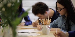 一群青年男女坐在桌旁，画着课程画着