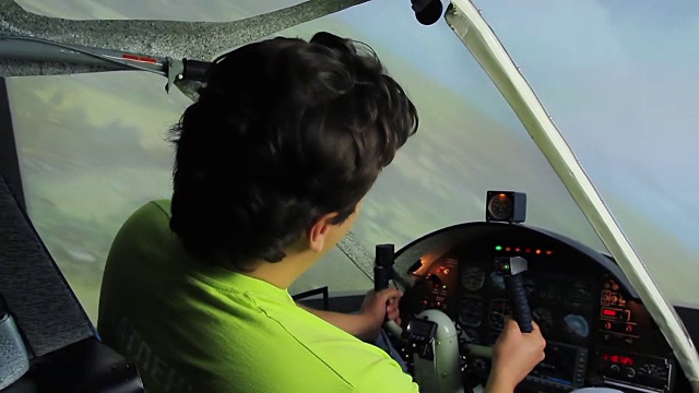 年轻男子坐在驾驶舱里，在飞机模拟器中享受飞行，爱好