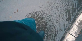 一个男人撑着伞走过雨中的水坑。莫慢，莫慢