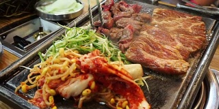 传统的韩国烧烤和配菜蔬菜。烤在大石盘上