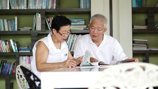亚洲资深夫妇一起在小图书馆看书和杂志。学习与研究概念视频素材模板下载