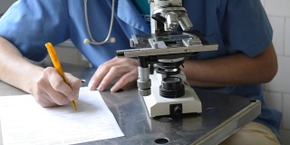 医生用显微镜在纸上记录信息