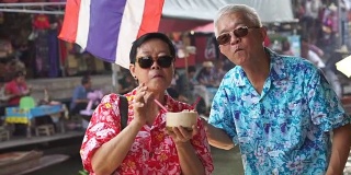 亚洲老年夫妇赴泰国水上市场旅游高清视频。喝新鲜椰汁