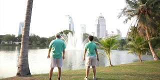 亚洲老夫妇以湖泊和城市公园为背景进行户外运动的视频。抽象热爱健康和自然