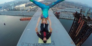 男人扶着女人在桥上，高空杂技瑜伽，肾上腺素