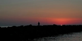 渔民在日落时的岩石上捕鱼-渔人海