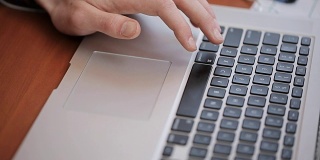 一个研究生使用一个科学数据库来编辑研究工作，使用笔记本触控板，在触控板上驱动一个手指