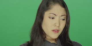 美丽的年轻亚洲女人开始哭泣，在一个绿色屏幕的工作室背景