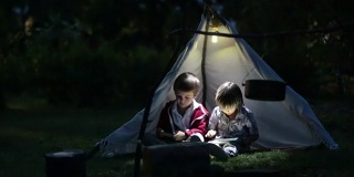 可爱的小弟弟们，晚上在帐篷里玩平板电脑和电话