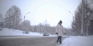 年轻女子在冬天过马路。Slowmotion