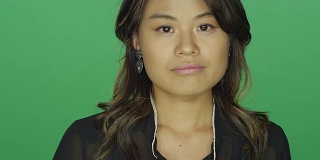 年轻的亚洲女人看起来很悲伤，在一个绿色屏幕的工作室背景