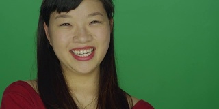 一个年轻的亚洲女人看起来非常沮丧和恼怒，在一个绿色屏幕的工作室背景