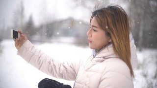 年轻女子在下雪时自拍。Slowmotion视频素材模板下载