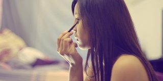 年轻的亚洲女人照镜子化妆