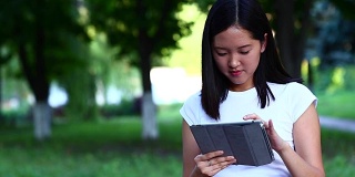 年轻美丽的亚洲人用平板电脑挥手，看着摄像头