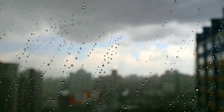 在暴风雨天，雨滴落在窗户上，城市天际线在背景中