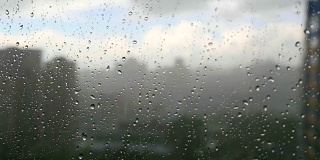 在暴风雨天，雨滴落在窗户上，城市天际线在背景中