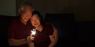亚洲老夫妇玩烟花，烟花，爆竹在晚上。庆祝生活的概念