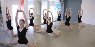 舞蹈课上女孩子们站着做伸展运动
