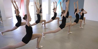漂亮的年轻女孩在舞蹈课上训练身体的柔韧性