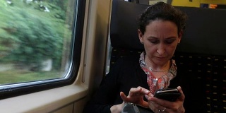 一名女子在通勤火车上查看手机。一个女人在看手机的照片