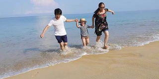 快乐亚洲一家一起在沙滩上跑步的慢镜头