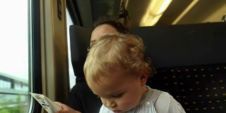 婴儿乘火车旅行的特写。妈妈用笔记本电脑和宝宝打电话。母亲和婴儿在火车上