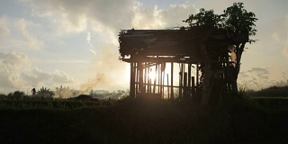 日落时分，在巴厘岛乌布，农民的棚屋在燃烧的稻田里