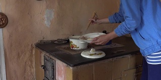 农妇从炉子上的煮锅里取出煮好的饺子。FullHD