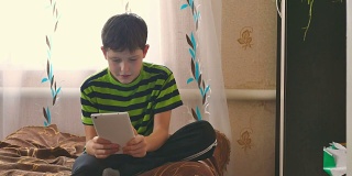 男孩坐在沙发上玩平板电脑，玩游戏，上网
