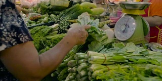 在市场上买新鲜蔬菜的女人。