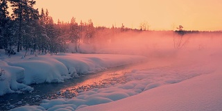 傍晚的玫瑰雾覆盖在白雪覆盖的森林和河流