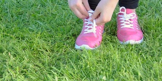 年轻女子跑步慢跑系鞋带在草地上