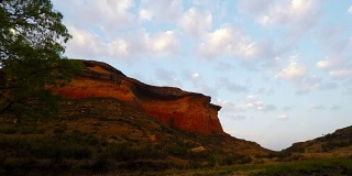 在雄伟的金门高地国家公园的岩石悬崖上的日落移动云，南非。时间流逝的视频。