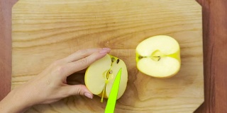 女人在木板上切苹果。烹饪食物