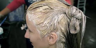近距离年轻女孩在美容沙龙的金发重绘