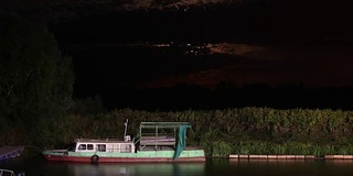 海港的夜景，旧船和月亮在背景中升起。时间流逝1080便士