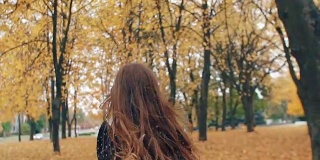 后视图快乐可爱的小女孩卷着头发穿过秋天的小巷在公园慢莫