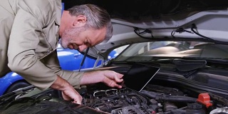 机械师在维修汽车引擎时使用数字平板电脑