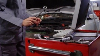 女机械师在维修汽车引擎时使用电脑视频素材模板下载