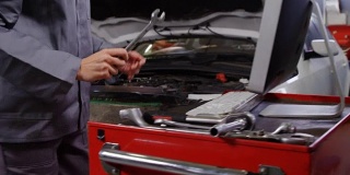 女机械师在维修汽车引擎时使用电脑