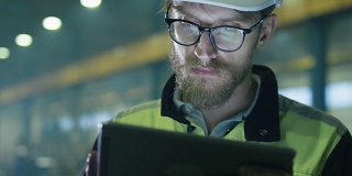 安全帽工程师正在一家重工业工厂里使用平板电脑。