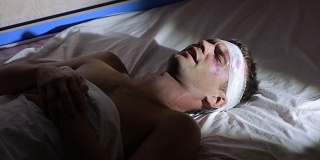 一个头部受伤的人躺在床上。缠着绷带。脸上有淤青。
