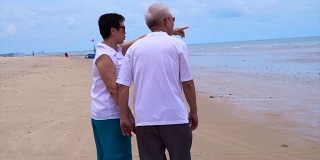 一对亚洲老年夫妇在海滩上愉快地散步。计划好退休生活，没有财务问题